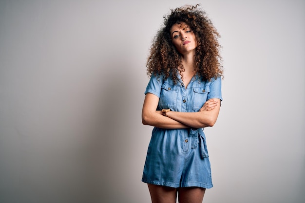 Foto grátis jovem mulher bonita com cabelos cacheados e piercing usando vestido jeans casual expressão de desaprovação cética e nervosa no rosto com braços cruzados pessoa negativa