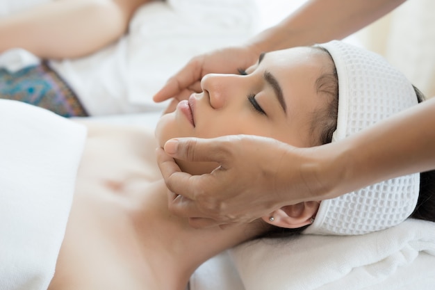 Jovem, mulher bonita, com massagem facial relaxante no spa.