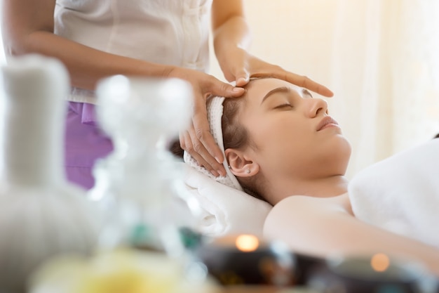 Jovem, mulher bonita, com massagem facial relaxante no spa.