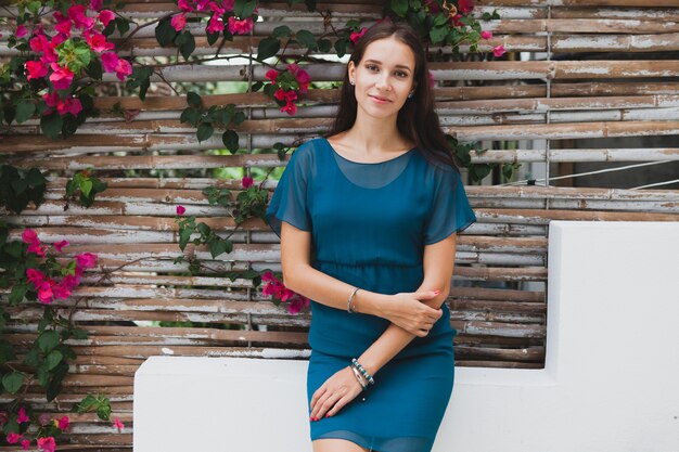 Jovem mulher bonita elegante em vestido azul, tendência da moda de verão, férias, jardim, terraço de hotel tropical, sorrindo