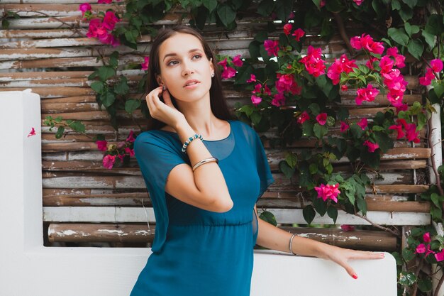 Jovem mulher bonita elegante em vestido azul, tendência da moda de verão, férias, jardim, terraço de hotel tropical, sorrindo