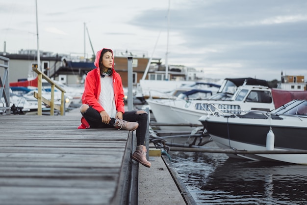 Jovem mulher bonita em um casaco vermelho no porto do iate. Estocolmo, Suécia