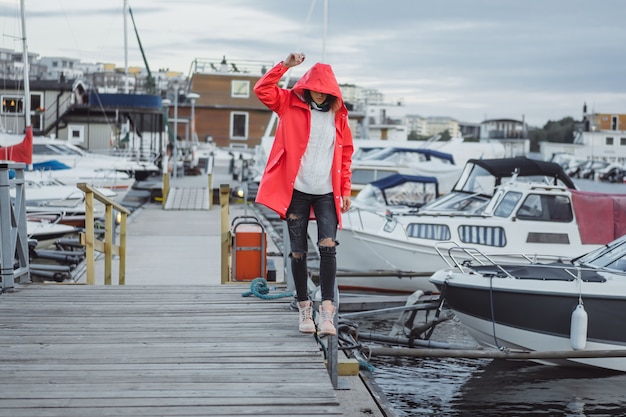Jovem mulher bonita em um casaco vermelho no porto do iate. Estocolmo, Suécia