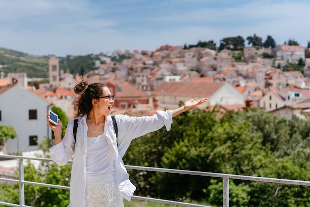 Foto grátis jovem mulher bonita na varanda com vista para uma pequena cidade na croácia