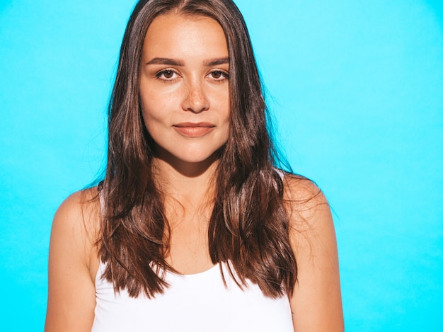 Jovem mulher bonita olhando. Menina na moda em roupas de verão casual. Fêmea engraçada e positiva posando perto de parede azul