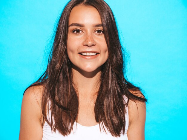 Jovem mulher bonita olhando. Menina na moda em roupas de verão casual. Fêmea engraçada e positiva posando perto de parede azul