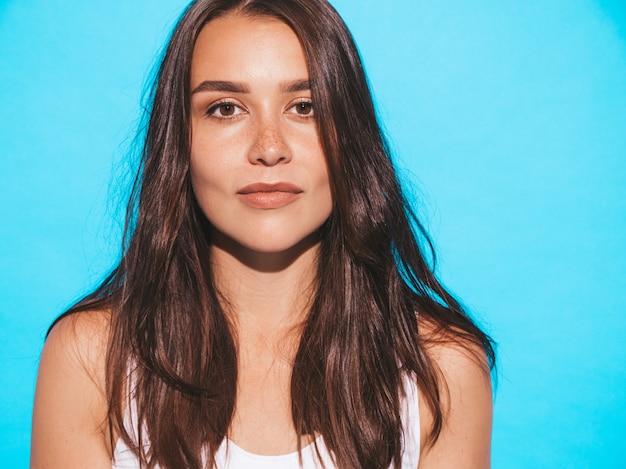 Jovem mulher bonita olhando. menina na moda em roupas de verão casual. fêmea engraçada e positiva posando perto de parede azul