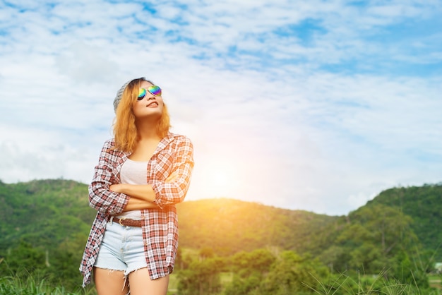 Jovem, mulher bonita que está moderno braços cruzados no meio natur