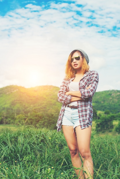 Jovem, mulher bonita que está moderno braços cruzados no meio natur