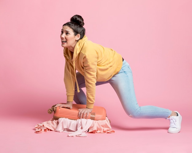 Foto grátis jovem mulher cabendo todas as suas roupas na bagagem