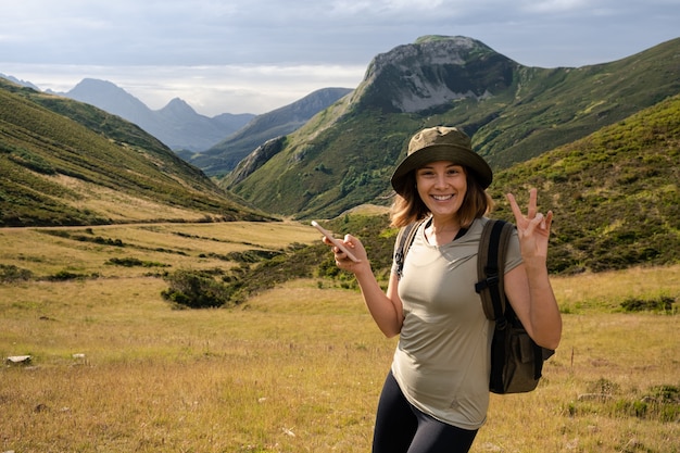 Jovem mulher caucasiana com um chapéu e uma mochila fazendo gestos engraçados