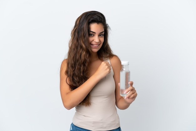 Jovem mulher caucasiana com uma garrafa de água isolada no fundo branco comemorando uma vitória