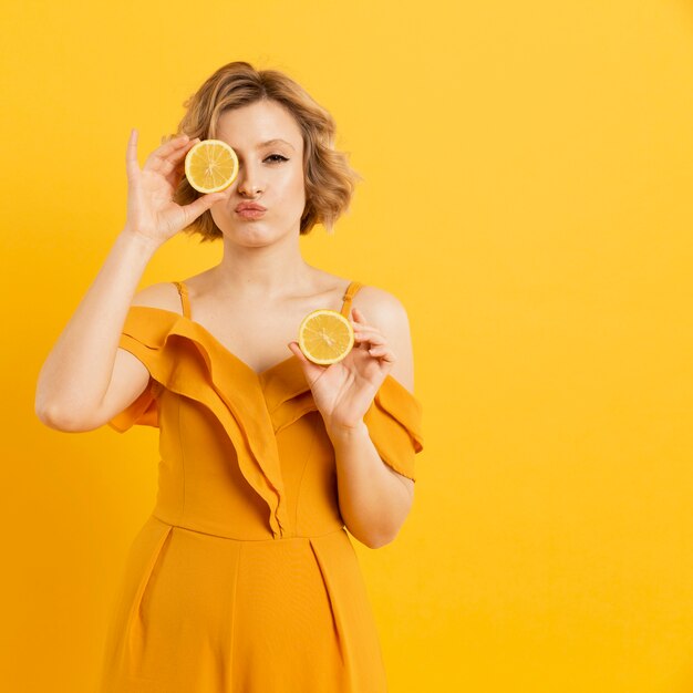 Jovem mulher cobrindo os olhos com rodelas de limão