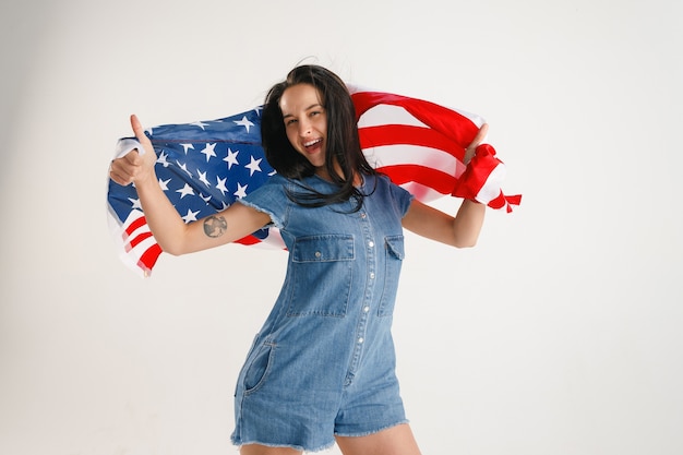 Jovem mulher com a bandeira dos Estados Unidos da América isolada no estúdio branco.
