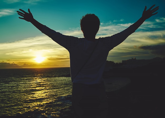 Jovem mulher com as mãos levantadas, cumprimentando o sol