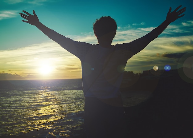 Jovem mulher com as mãos levantadas, cumprimentando o sol