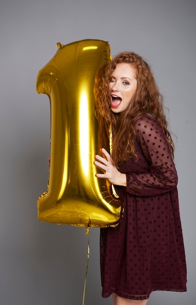 Foto grátis jovem mulher com balão dourado comemorando o primeiro aniversário de sua empresa