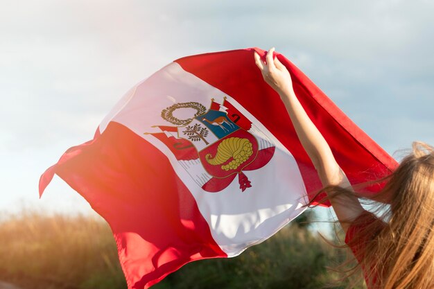 Jovem mulher com bandeira do Peru ao ar livre