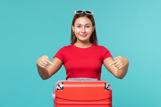 Jovem mulher com bolsa vermelha sorrindo no espaço azul de frente