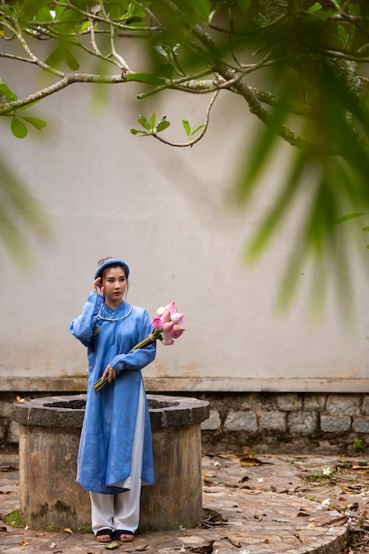 Foto grátis jovem mulher com buquê de flores vestindo traje ao dai