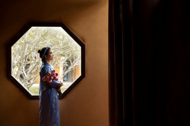 Foto grátis jovem mulher com buquê de flores vestindo traje ao dai