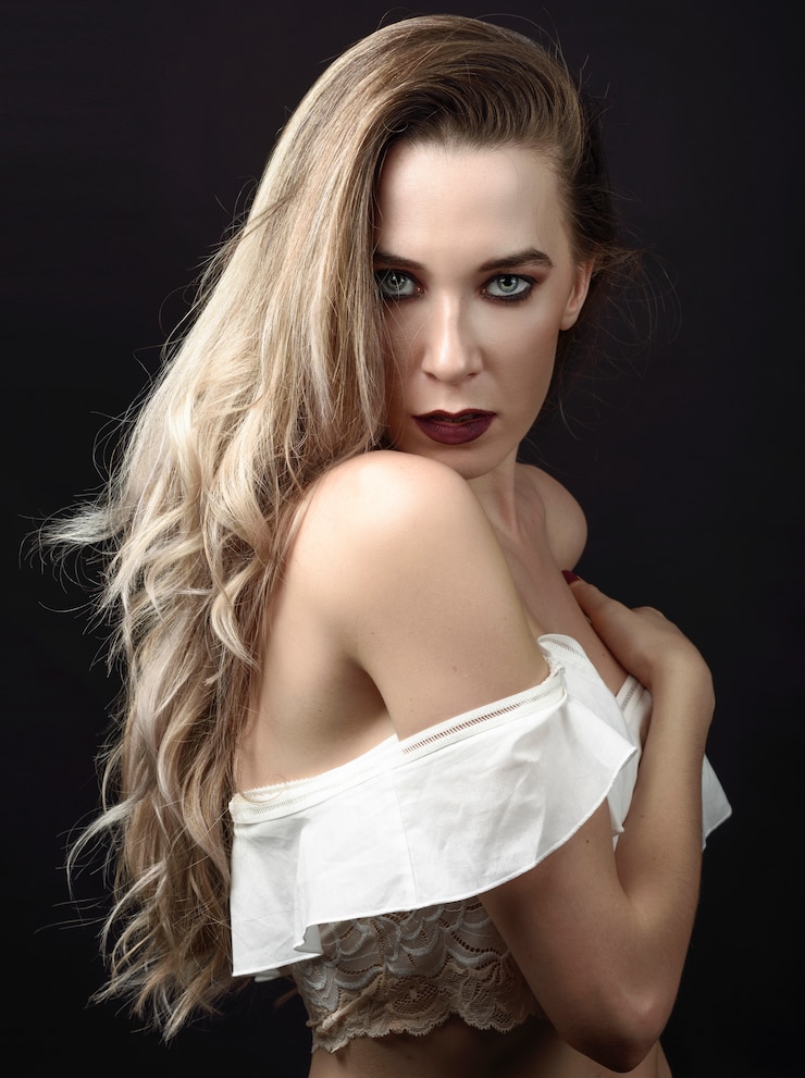 Foto grátis jovem mulher com cabelo longo e olhos azuis contra o fundo preto com composição roxa.