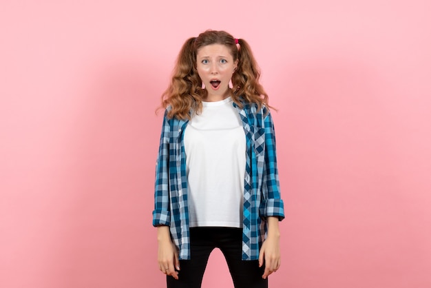 Jovem mulher com camisa quadriculada posando em um fundo rosa jovem mulher cor emoções modelo garoto