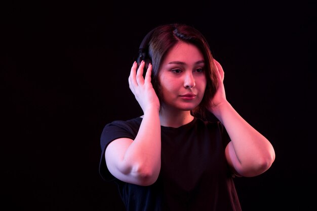 Jovem mulher com camiseta preta usando fones de ouvido