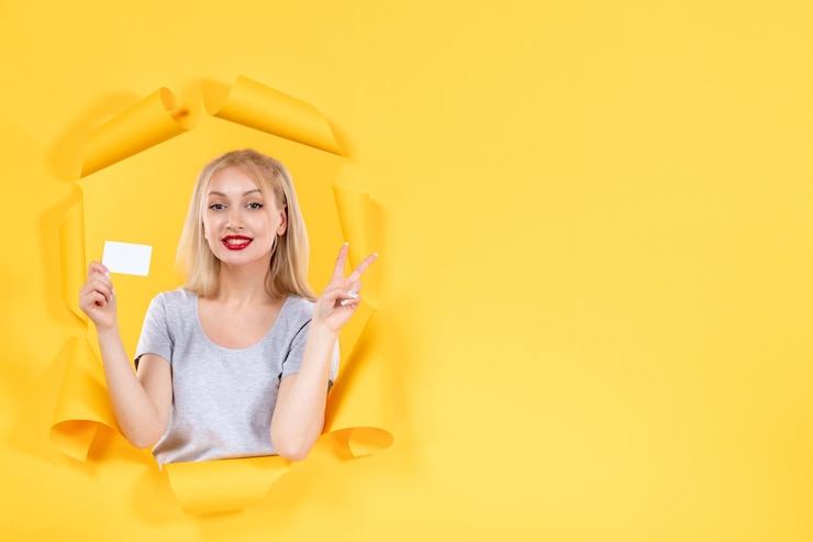 Foto grátis jovem mulher com cartão de crédito branco na superfície amarela