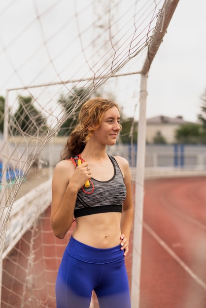 Jovem mulher com corda, sentado no portão de futebol