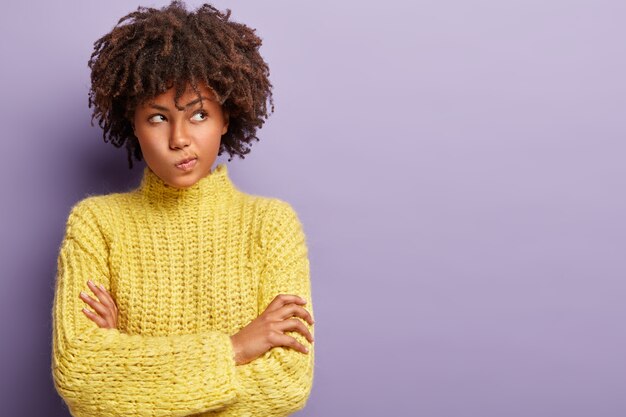 Jovem mulher com corte de cabelo afro e suéter amarelo