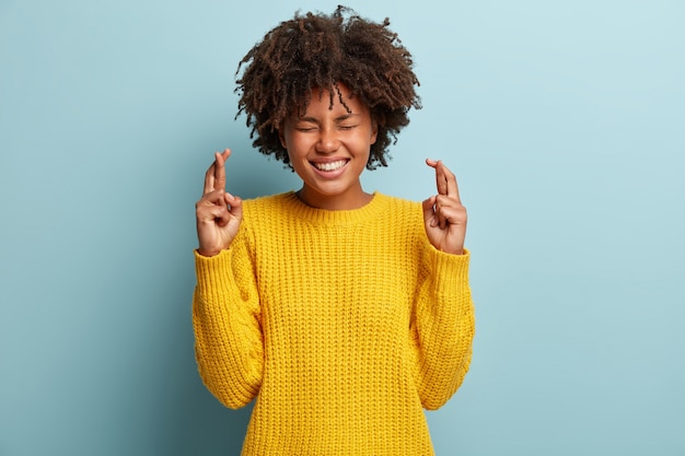 Jovem mulher com corte de cabelo afro e suéter amarelo