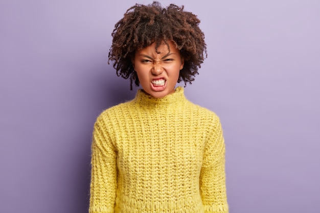 Jovem mulher com corte de cabelo afro e suéter amarelo