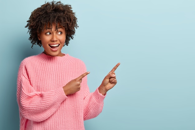 Jovem mulher com corte de cabelo afro e suéter rosa