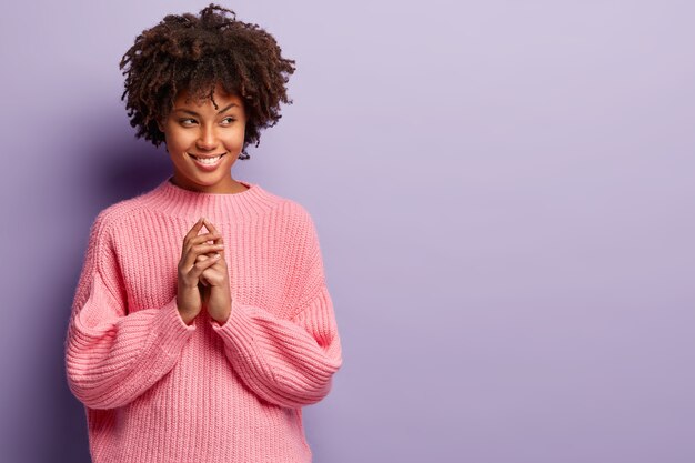 Jovem mulher com corte de cabelo afro e suéter rosa