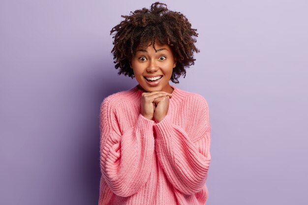 Jovem mulher com corte de cabelo afro e suéter rosa