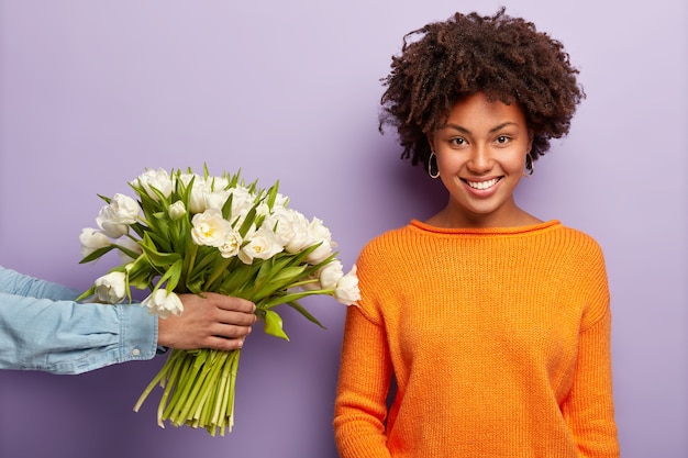 Foto grátis jovem mulher com corte de cabelo afro recebendo buquê de flores brancas