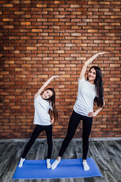 Jovem mulher com filha em roupas esportivas, leggings e sutiã praticando ioga, linda garota de pé .. Juntos ..