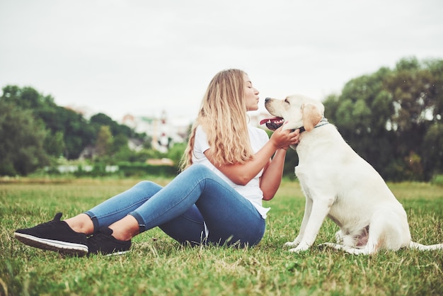 jovem mulher com labrador ao ar livre. Mulher em uma grama verde com cachorro labrador retriever.