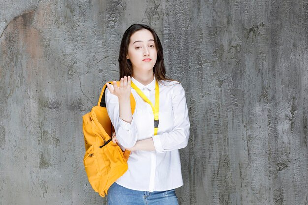 Jovem mulher com mochila em cima de parede cinza. Foto de alta qualidade