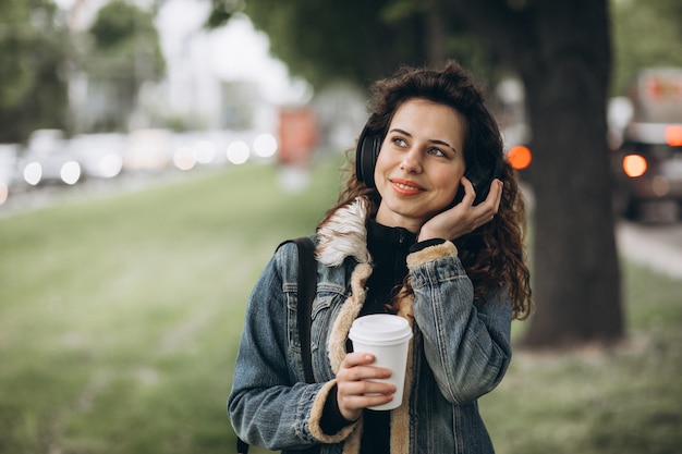 Jovem mulher com música e bebendo café