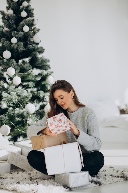 Jovem mulher com presentes de natal perto da árvore de natal