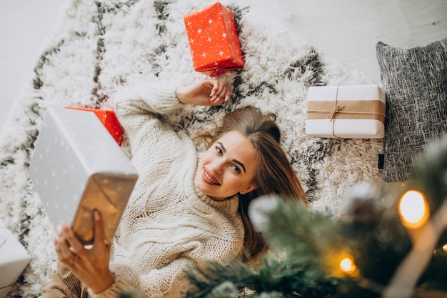 Jovem mulher com presentes de natal perto da árvore de natal