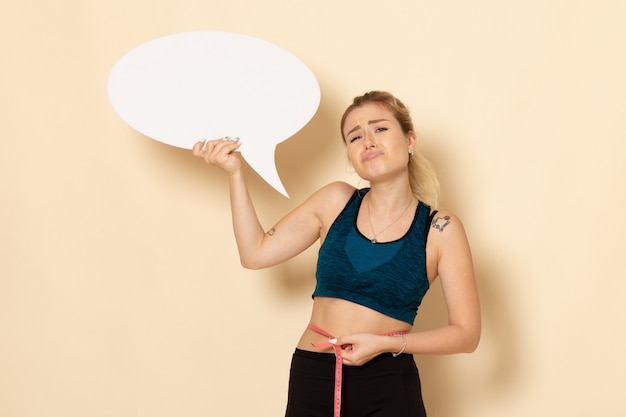 Jovem mulher com roupa esportiva segurando uma placa branca de frente