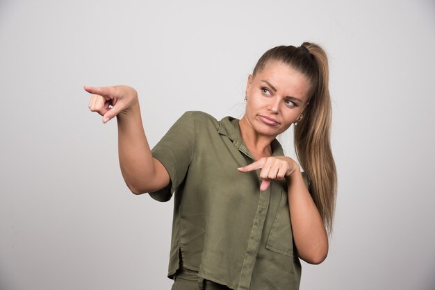 Jovem mulher com roupa verde, apontando algo.