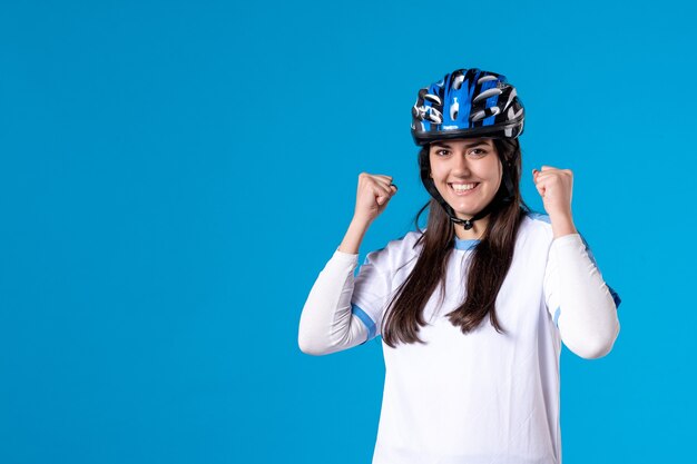 Jovem mulher com roupas esportivas e capacete na parede azul de frente