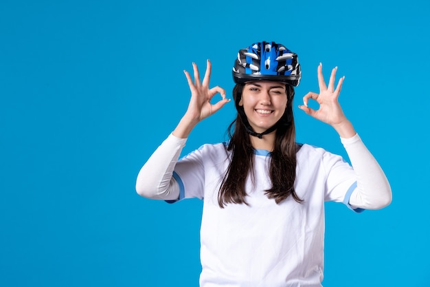 Jovem mulher com roupas esportivas e capacete na parede azul de frente