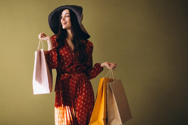 Jovem mulher com sacolas de compras em um lindo vestido e chapéu