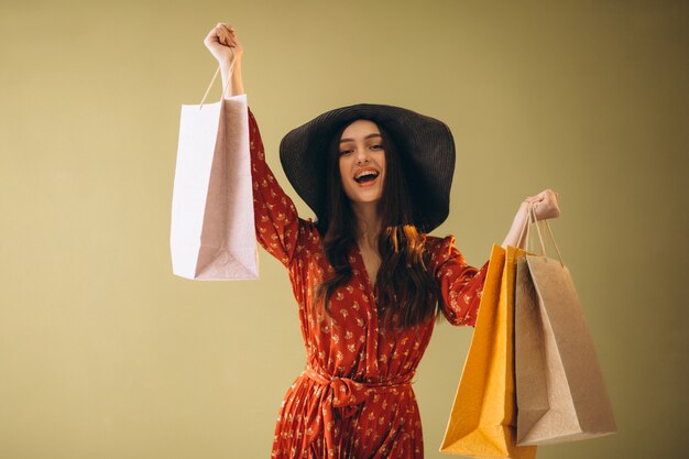 Jovem mulher com sacolas de compras em um lindo vestido e chapéu