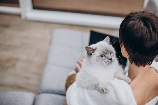 Jovem mulher com um gato trabalhando em um laptop de casa